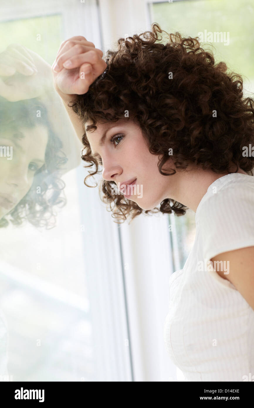 young woman standing by the window Stock Photo