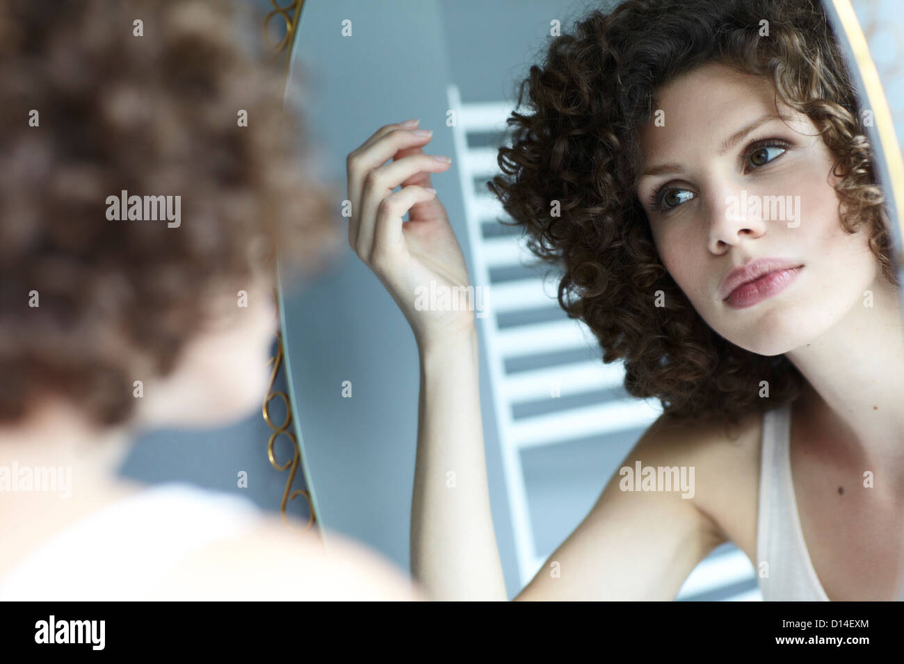 young woman checking her hair in the mirror Stock Photo