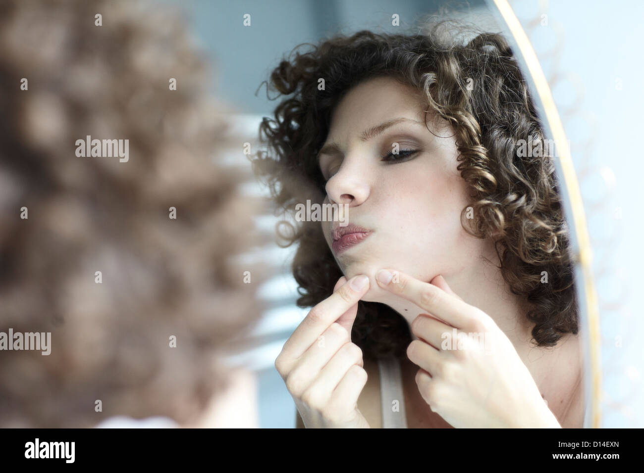 young woman checking her face in the mirror Stock Photo