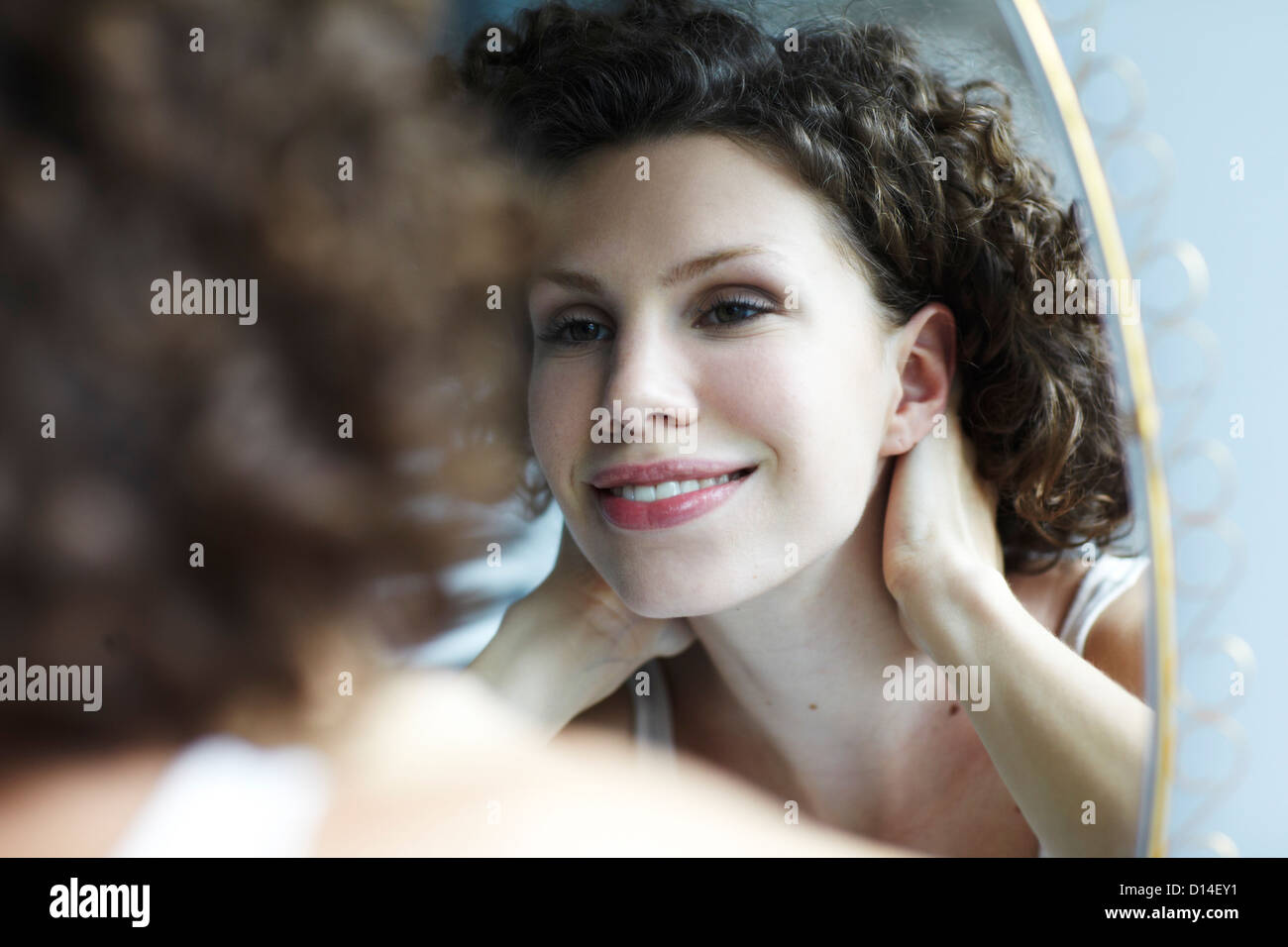 young woman smiling at her reflection in the mirror Stock Photo