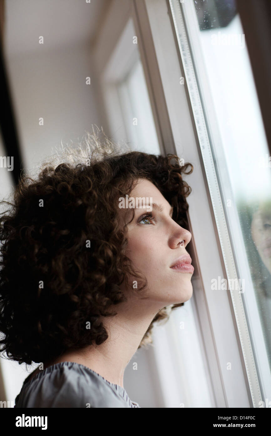 portrait of young woman looking out of window Stock Photo