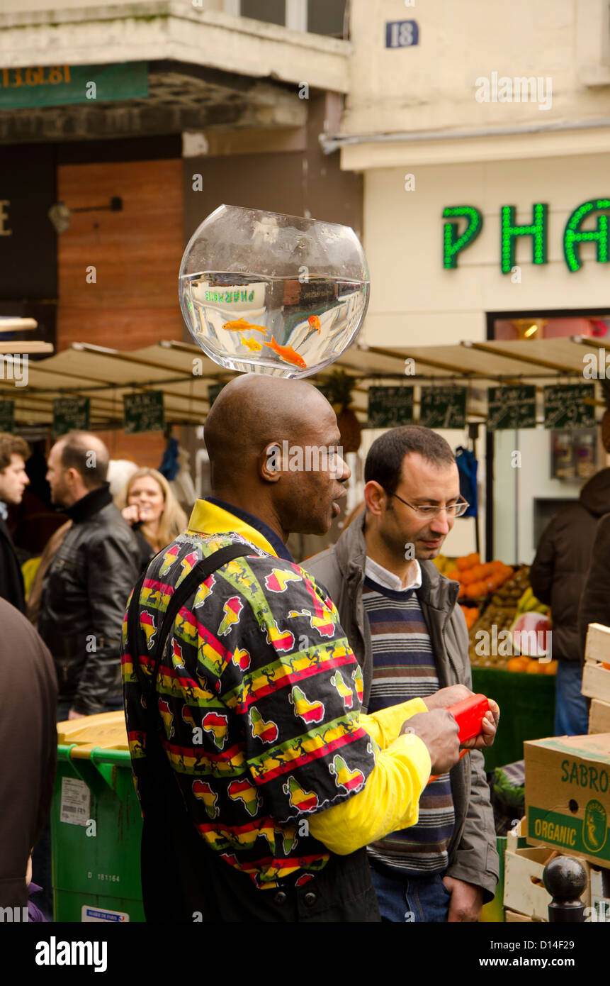 Street artist giving performance with fishbowl on head at place d