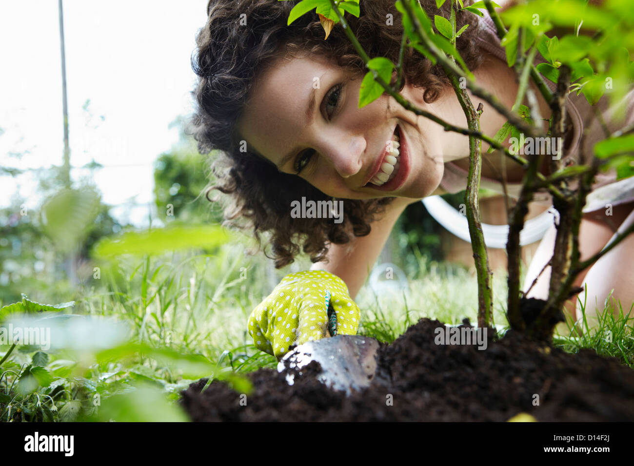 portrait of young woman planting a plant in the garden Stock Photo