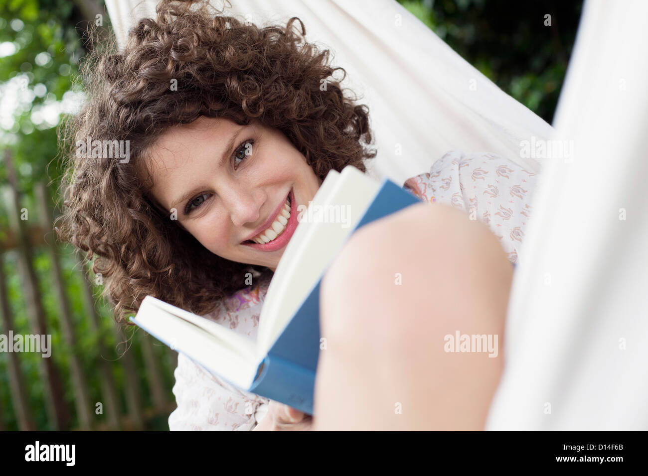 young woman lying in hammock in garden reading Stock Photo