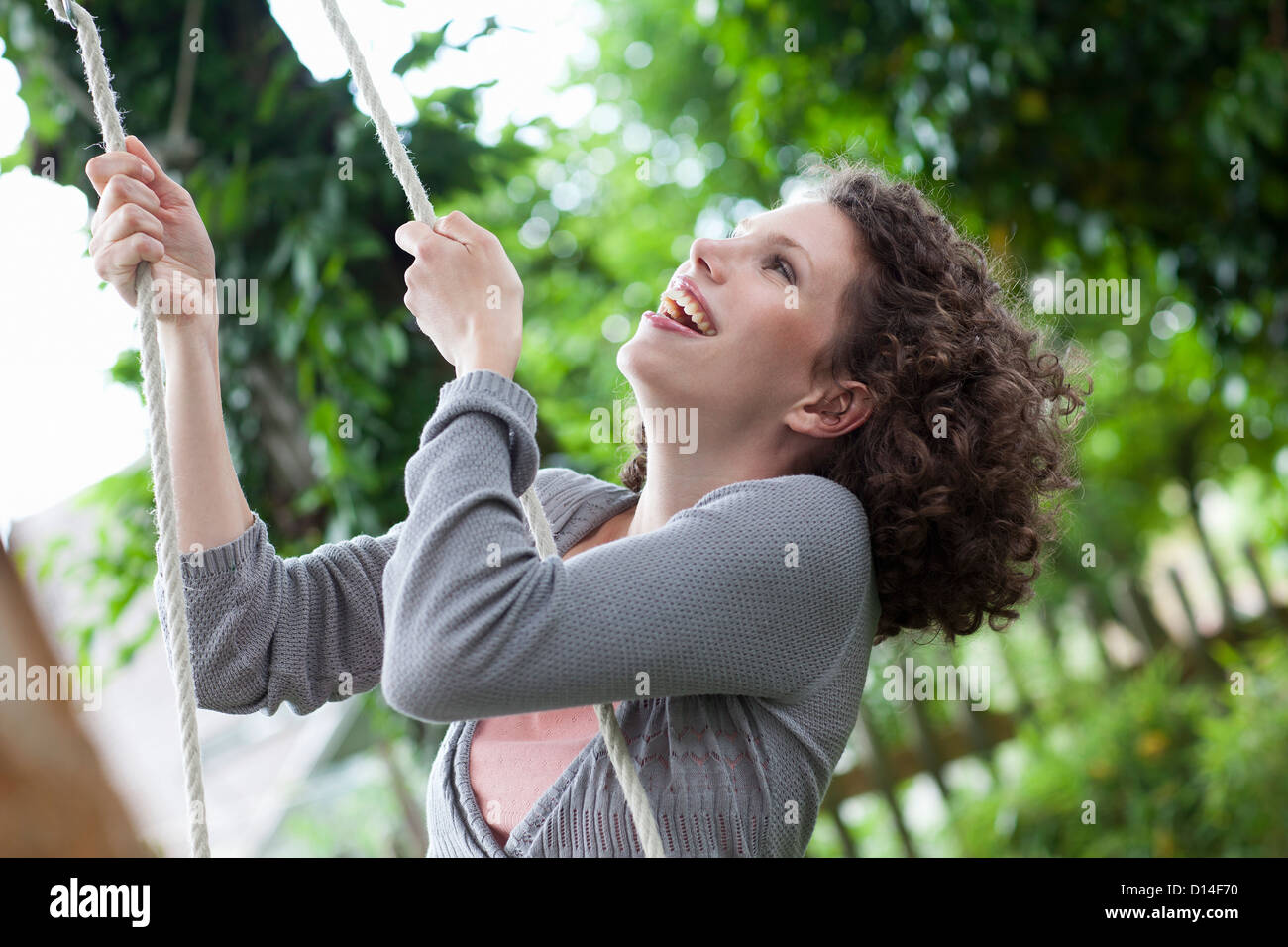 portrait of young woman in garden on swing Stock Photo