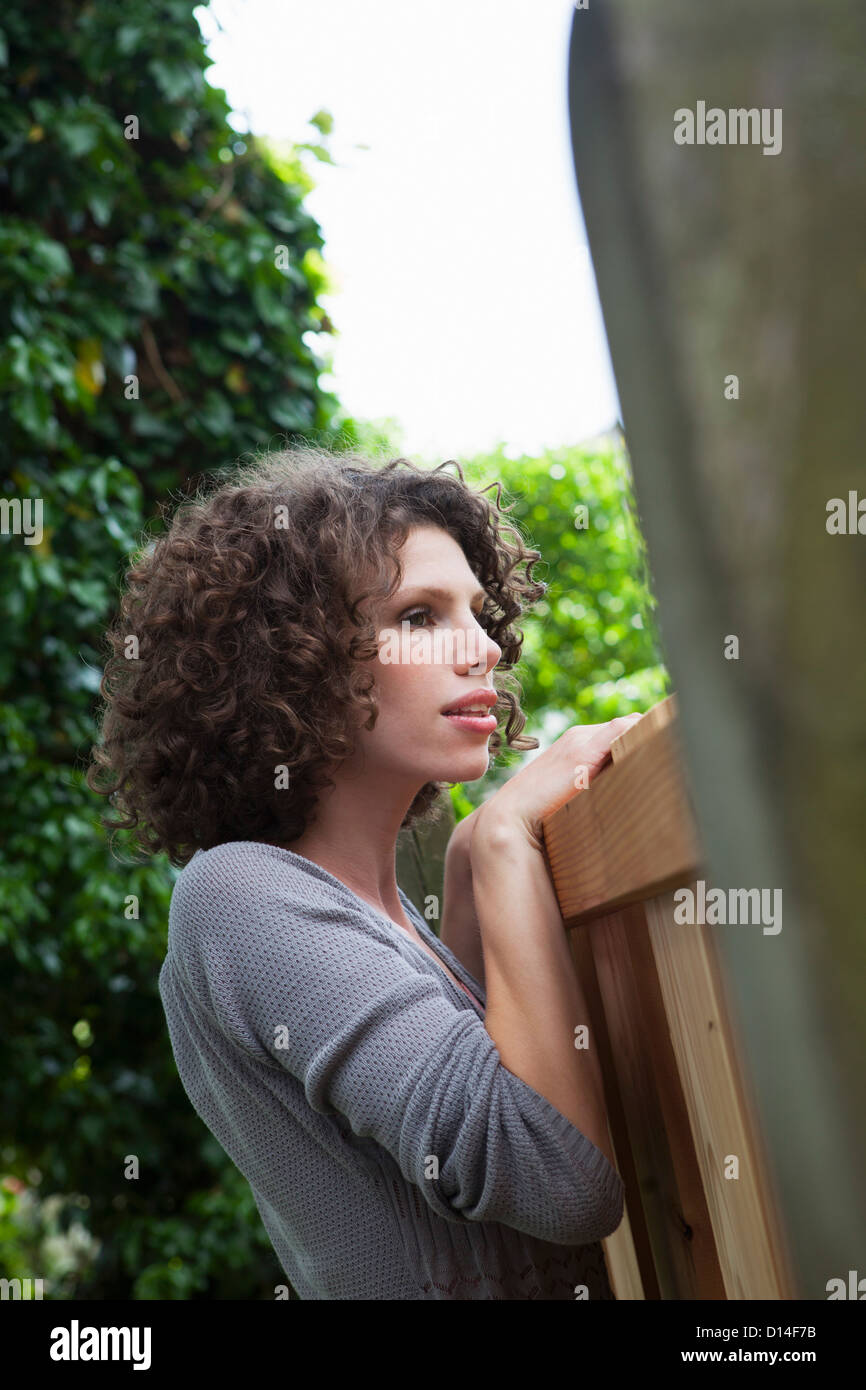 portrait of young woman looking over garden fence Stock Photo