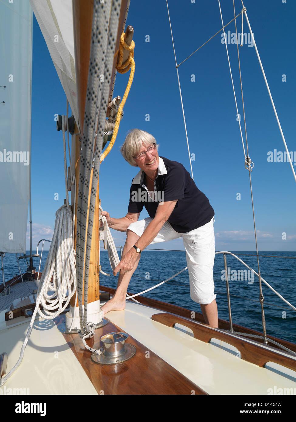 Woman adjusting rigging on sailboat Stock Photo
