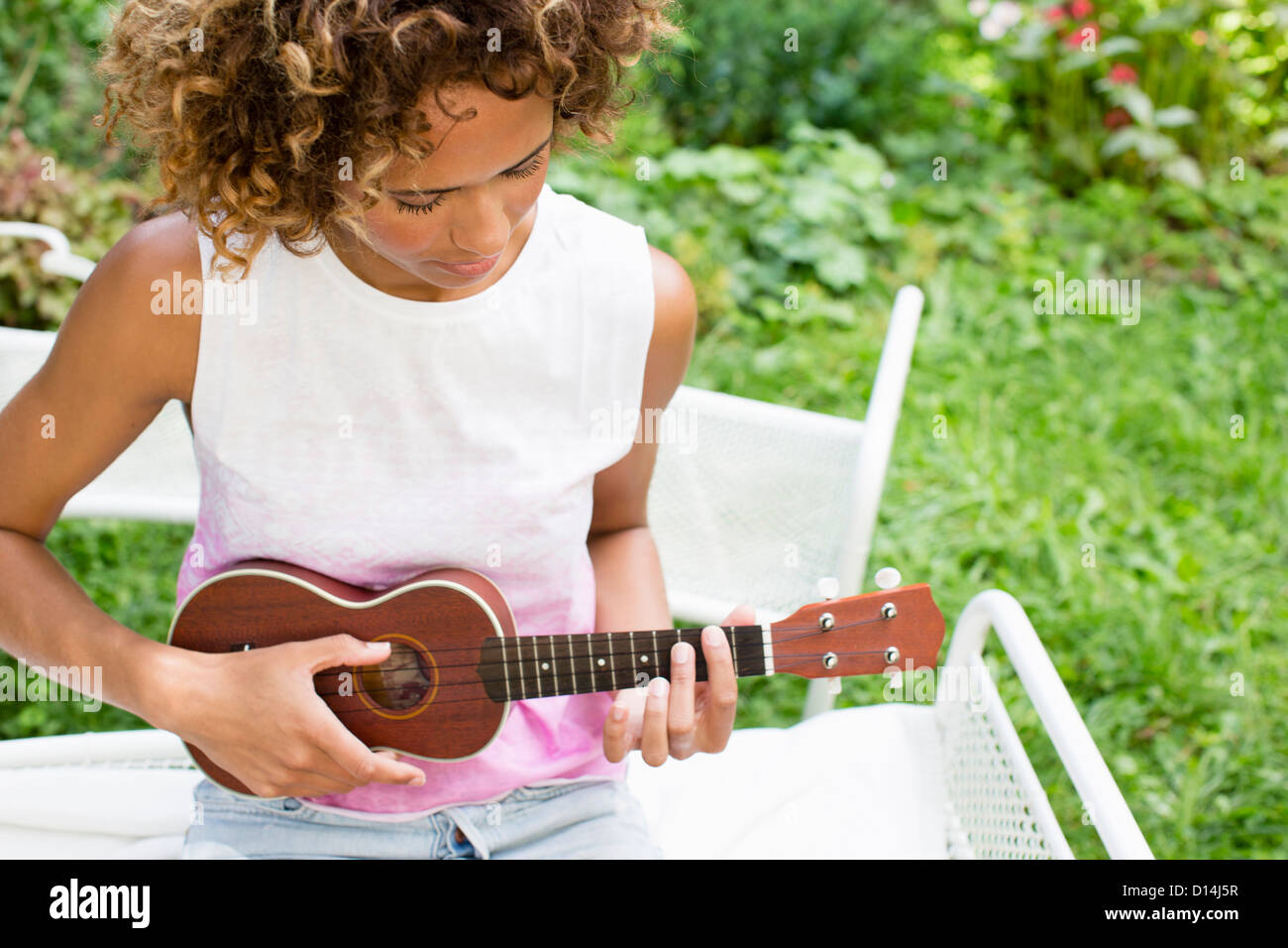 Woman playing ukulele in backyard Stock Photo