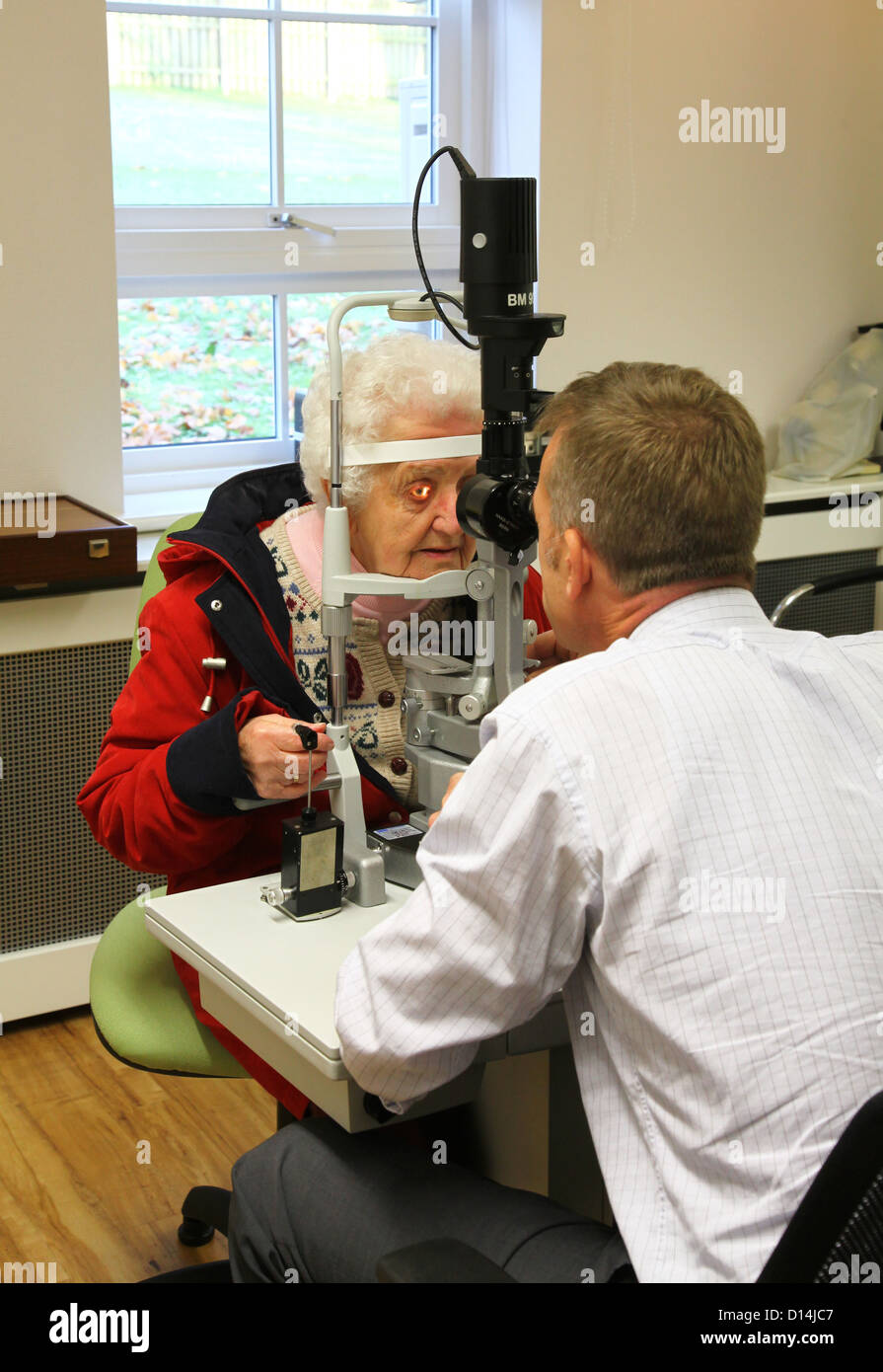 An old woman having her eyes tested for cataracts by a consultant ophthalmologist Stock Photo