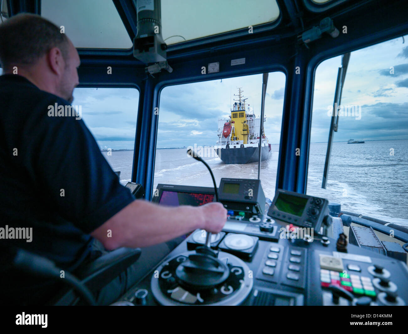 Worker driving tugboat in wheelhouse Stock Photo