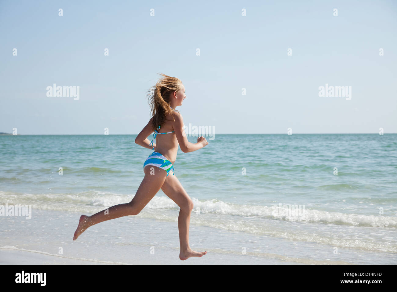 USA, Florida, St. Petersburg, girl (12-13) running along beach Stock Photo