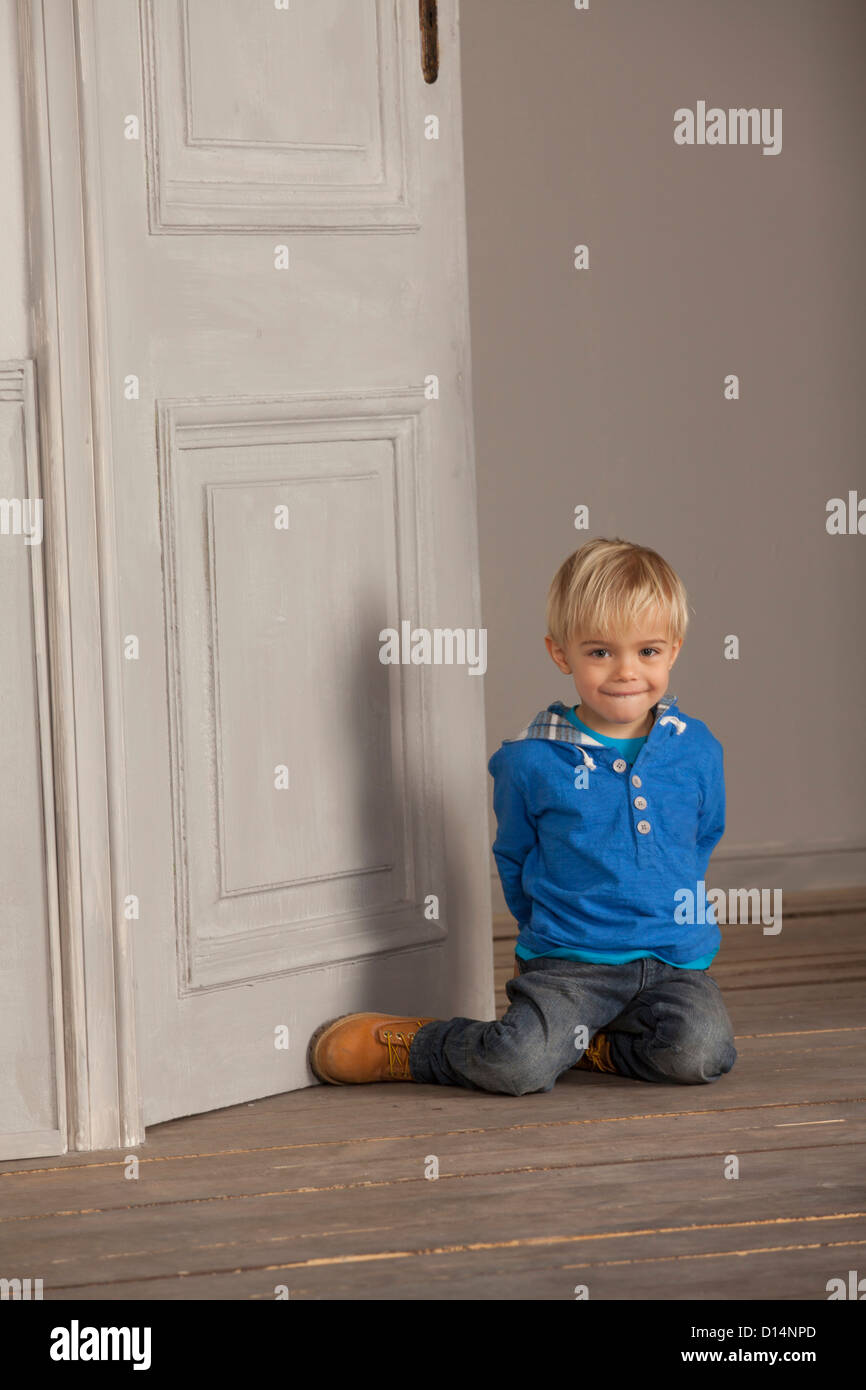 Boy sitting on wooden floor Stock Photo