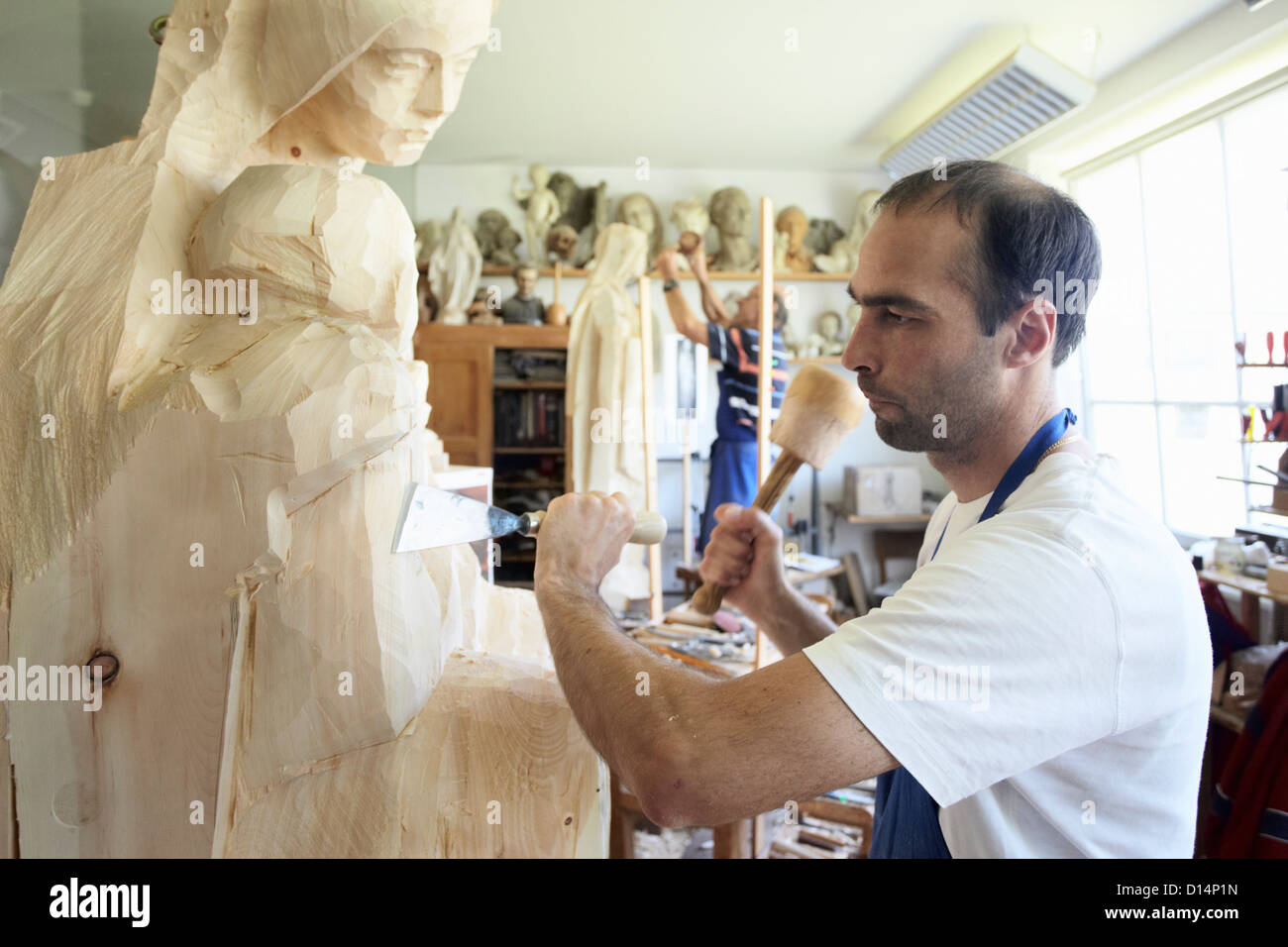 Sculptor chiseling figure from wood Stock Photo