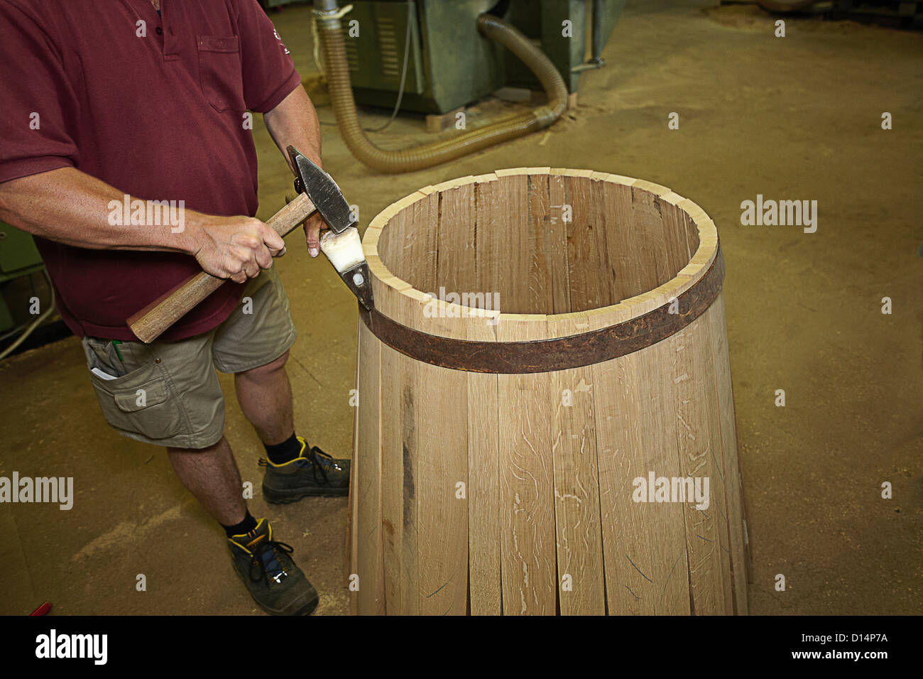 Worker hammering barrel in shop Stock Photo