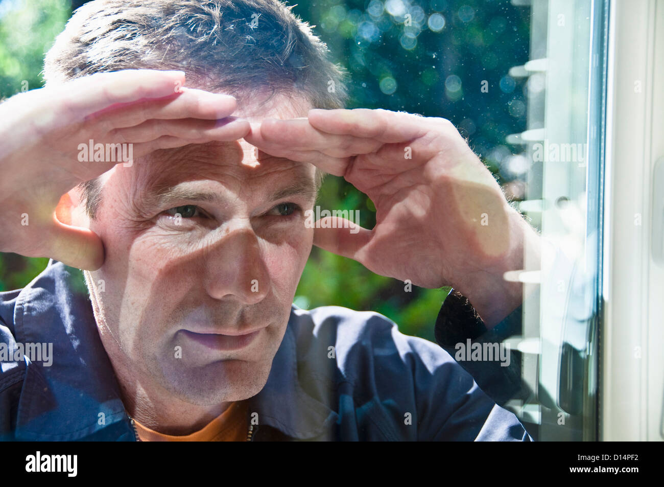 Man peering in window of house Stock Photo