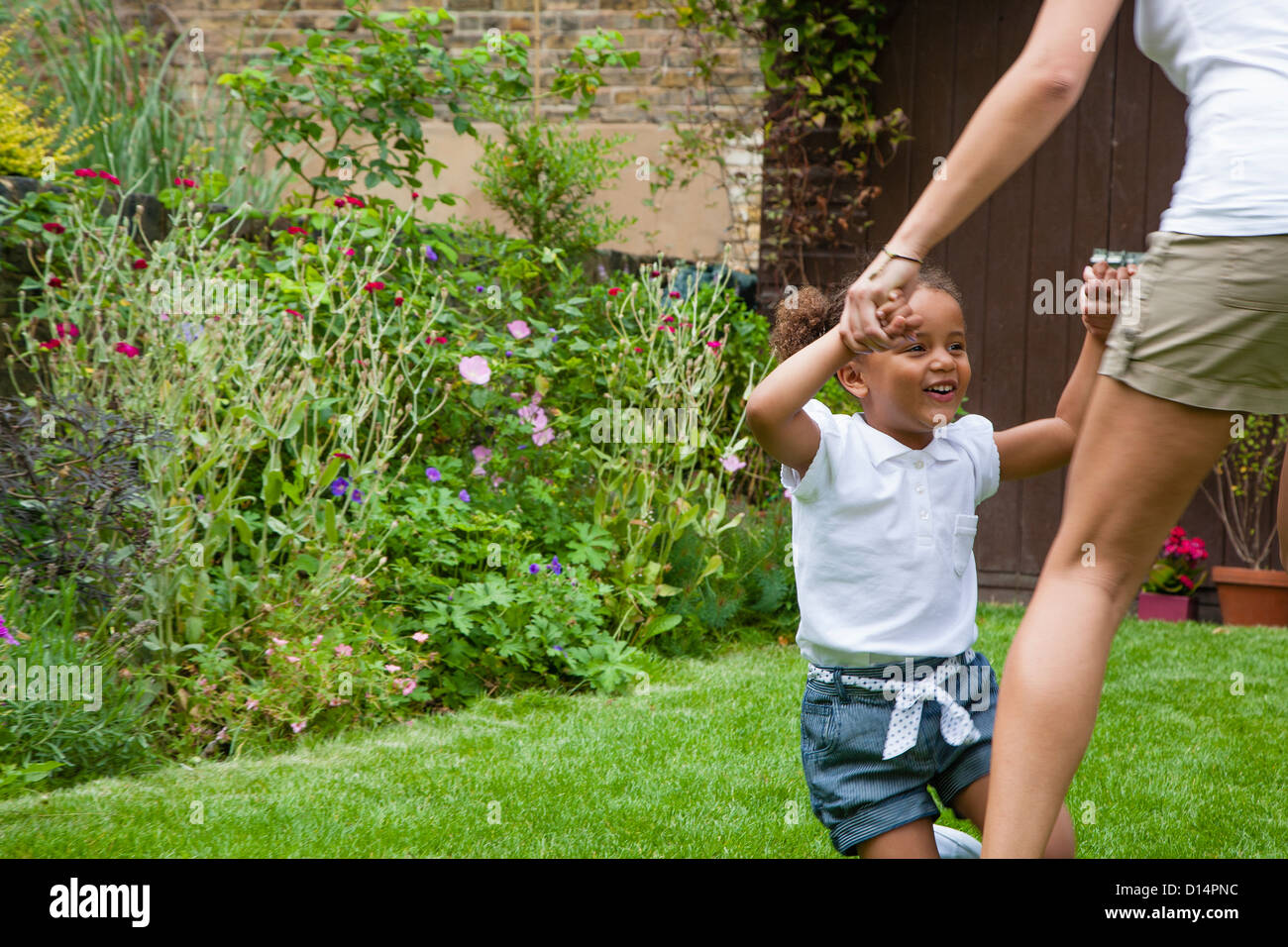 Mother and daughter dancing in garden Stock Photo