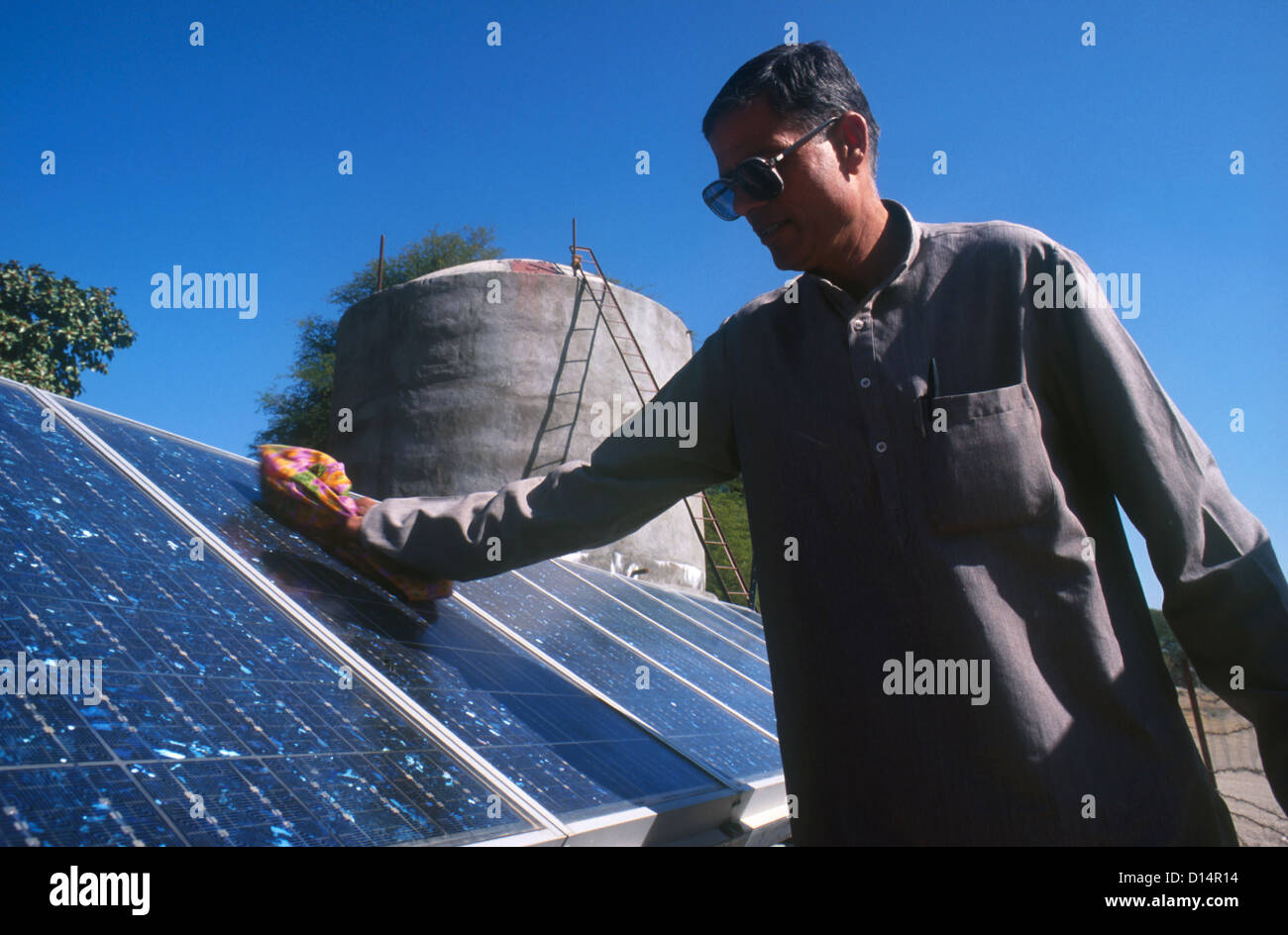 India Rajasthan , man clean solar panel of solar powered water pump to