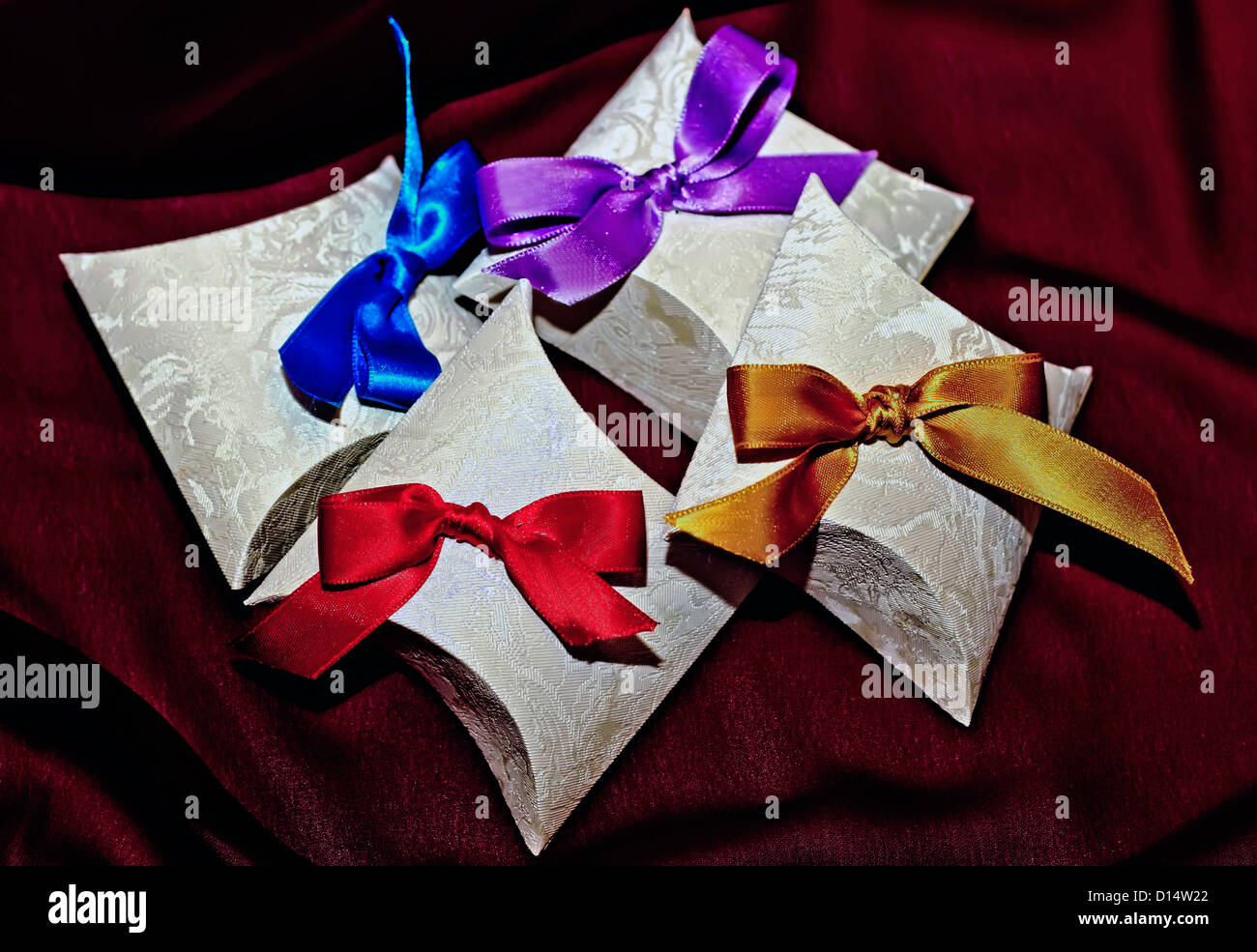 Paper boxes with colorful bows on maroon Stock Photo