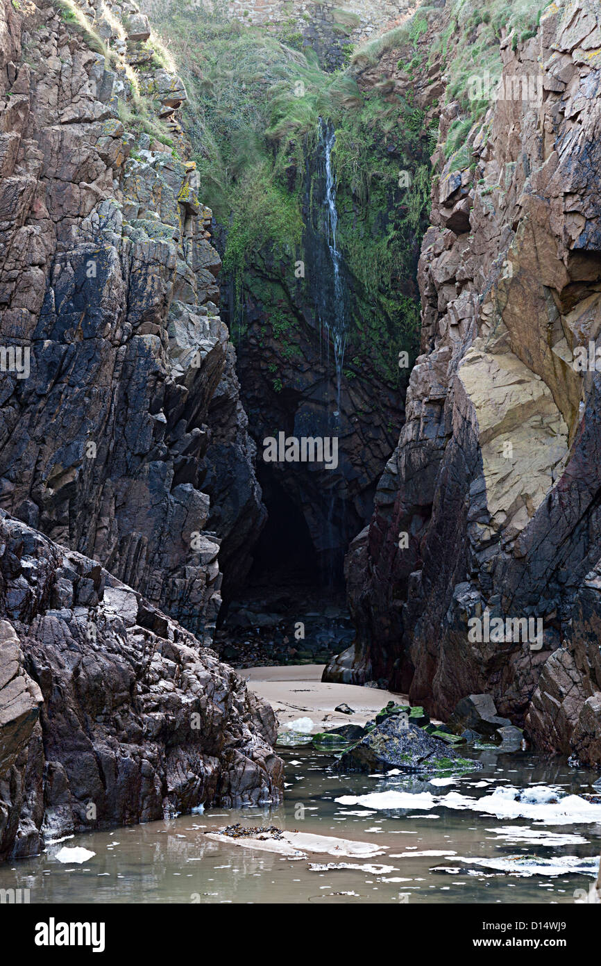 Waterfall in narrow cleft in sea cliffs at Plemont, Jersey; Channel Islands, UK Stock Photo