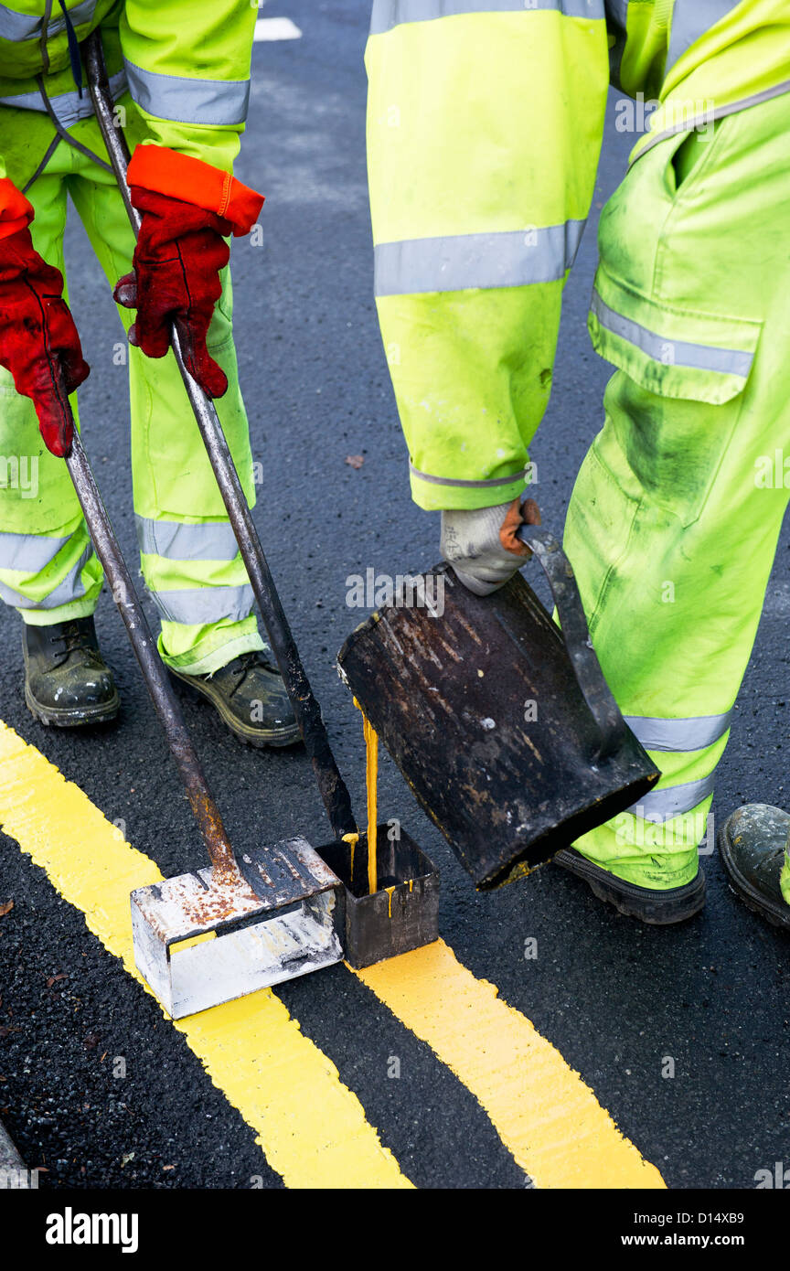 Highway maintenance workers laying down double yellow lines Stock Photo