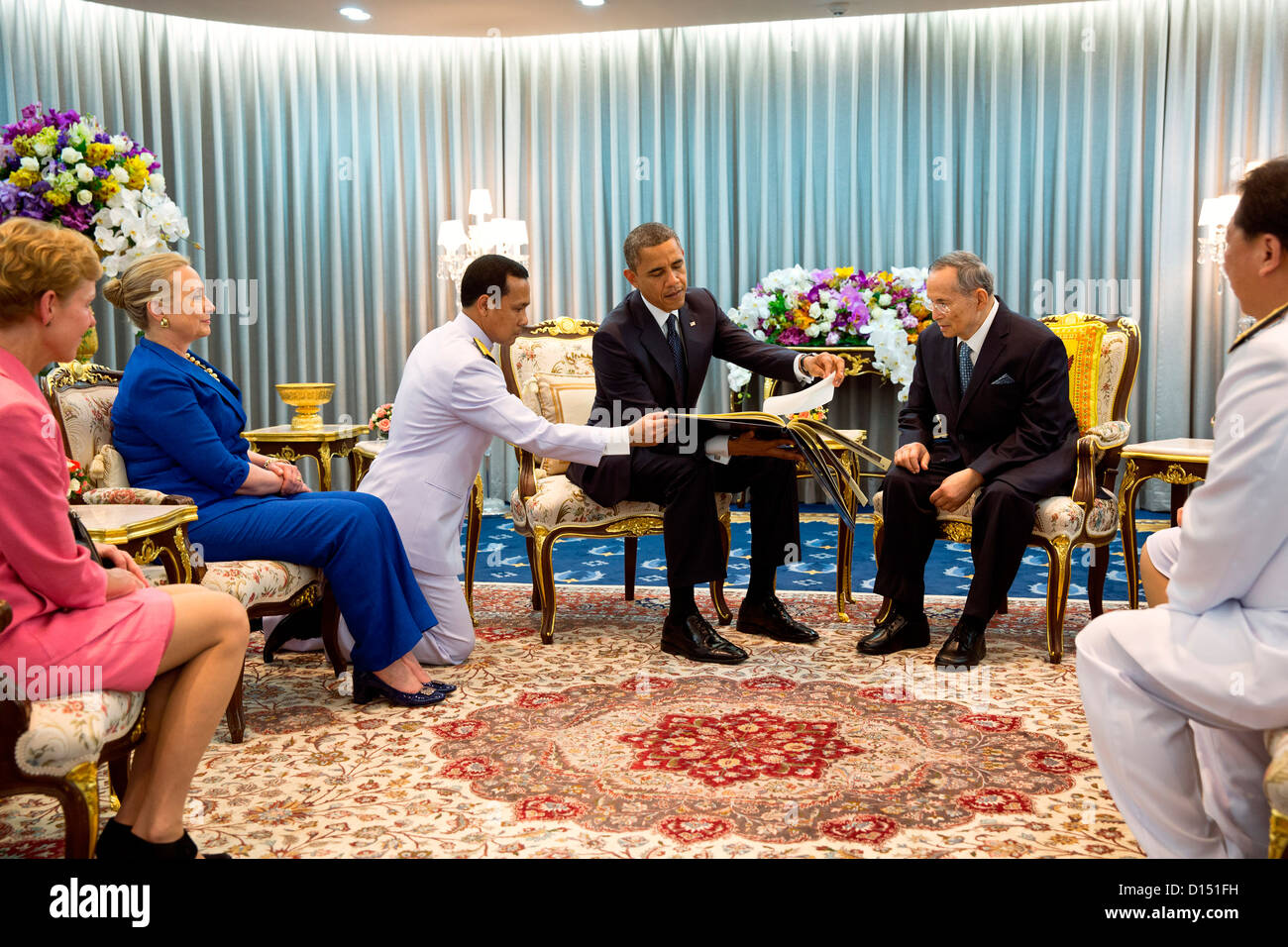 US President Barack Obama presents a gift to King Bhumibol Adulyadej of Thailand during their meeting at Siriraj Hospital in November 18, 2012 in Bangkok, Thailand. President Obama presented a photo album containing photos of the King with US Presidents and First Ladies dating back to President Eisenhower. US Ambassador to Thailand Kristie Kenney with Secretary of State Hillary Rodham Clinton are seated at left. Stock Photo