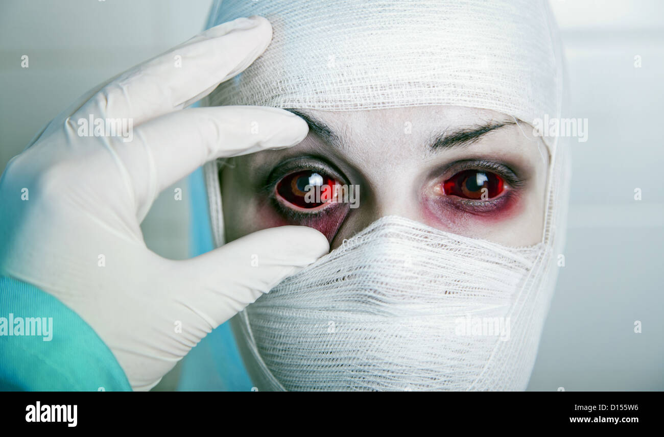 Evil doctor checking results of genetic experiment, opening eye of bandaged  patient Stock Photo - Alamy