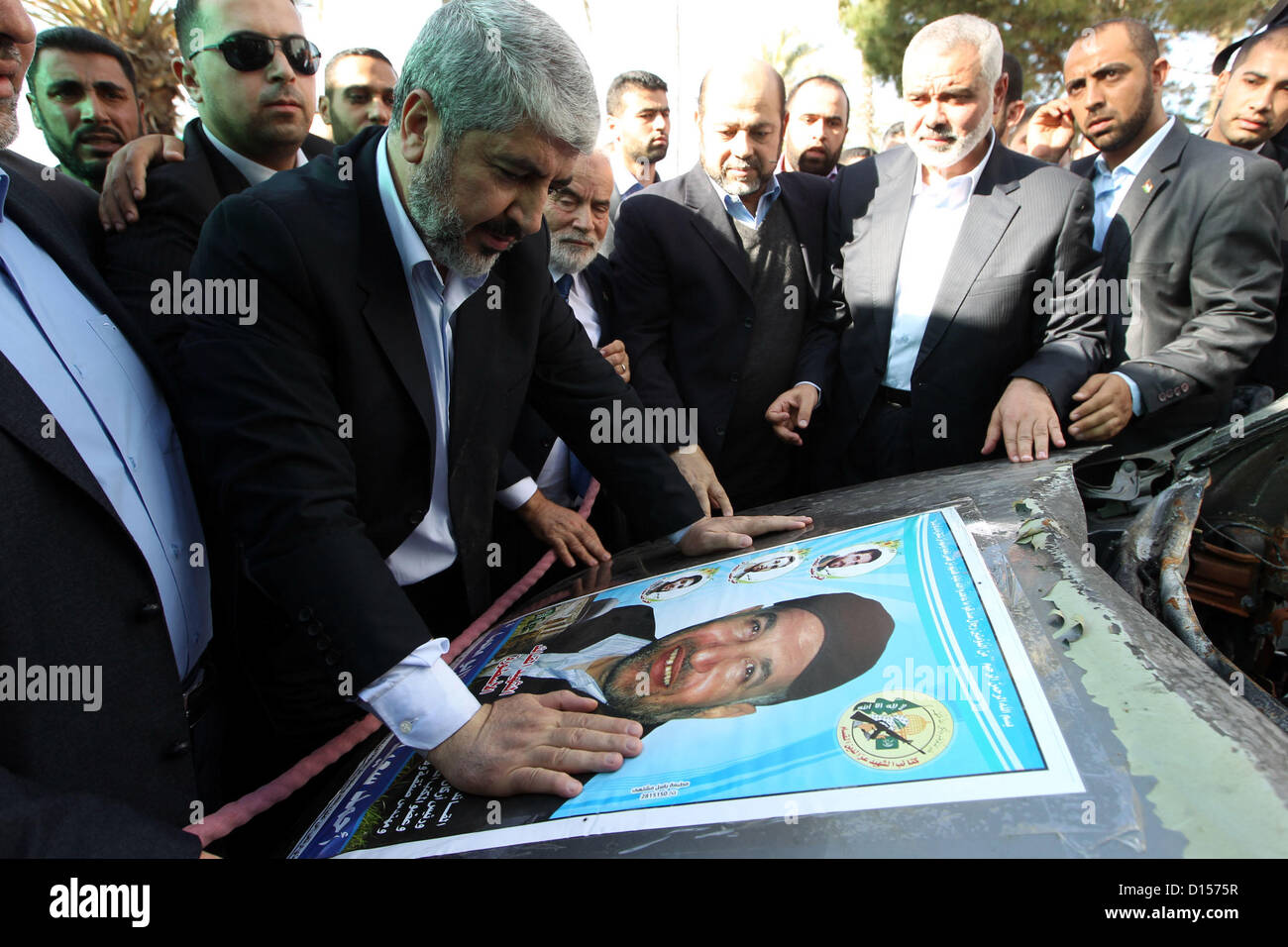 Dec. 7, 2012 - Gaza City, Gaza Strip, Palestinian Territory - Hamas chief Khaled Meshaal (2nd L) prays beside a poster depicting late Hamas military commander Ahmed Al-Jaabari which pasted on the remains of the car that he was riding in when he was killed in an Israeli air strike, at Rafah Crossing in southern Gaza Strip December 7, 2012. Meshaal ended decades of exile from Palestinian land on Friday with a triumphal first ever visit to the Gaza Strip that underscored the Islamist group's growing confidence following its latest conflict with Israel  (Credit Image: © Mohammed Ostaz/APA Images/Z Stock Photo