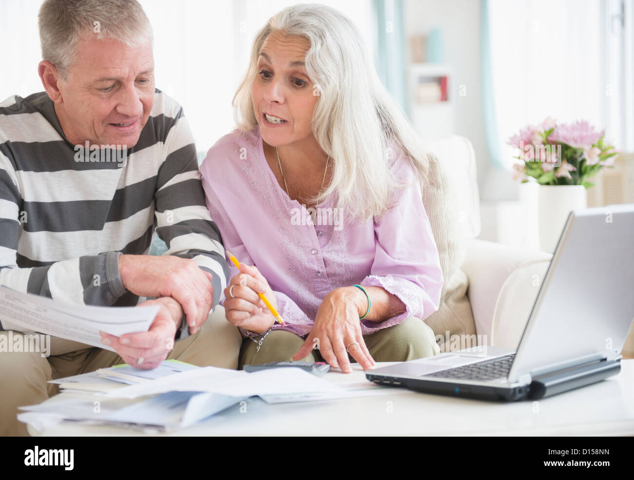 USA, New Jersey, Jersey City, Elderly couple with laptop and documents sitting in living room Stock Photo