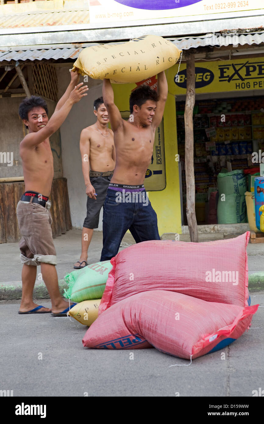 Teenage boys carry heavy sacks of white rice in Bogo City, Cebu Island