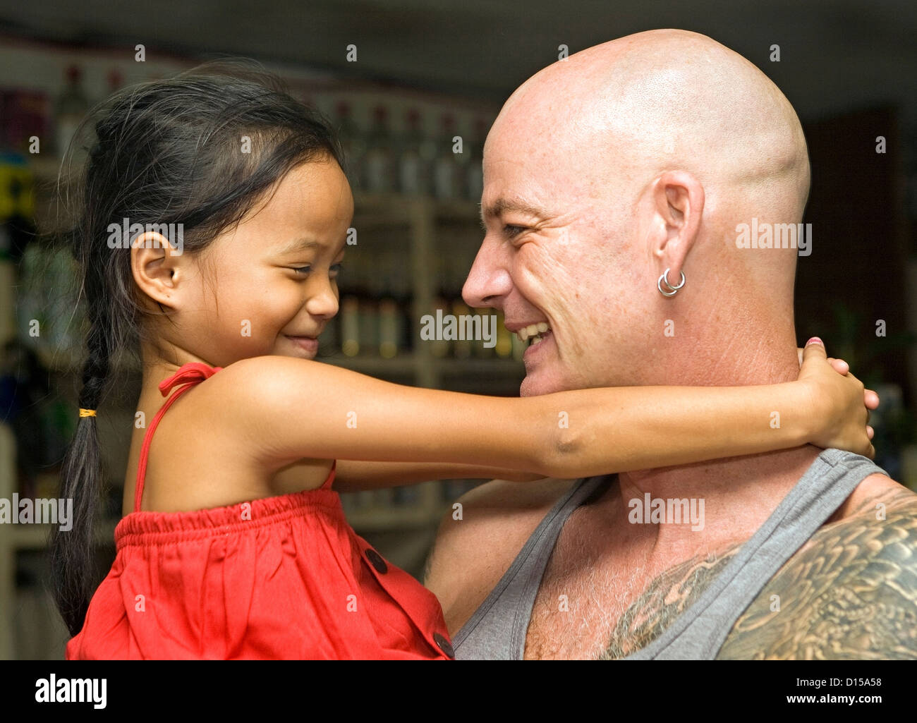 Caucasian man and beautiful, young Filipino girl hugging and smiling at each other. Stock Photo