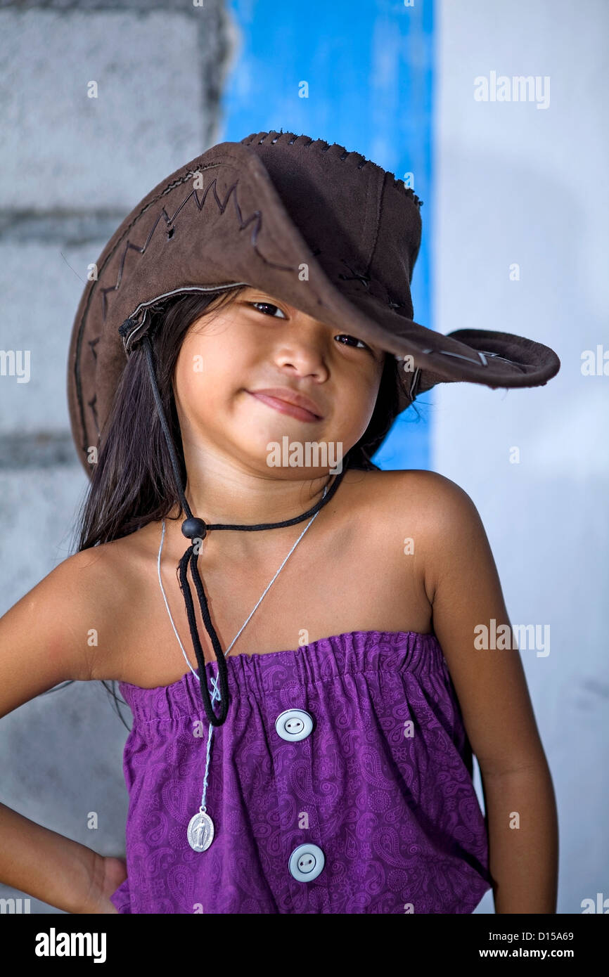 A cute, young Filipino girl models a brown, leather hat and a purple dress  in the Philippines. Stock Photo