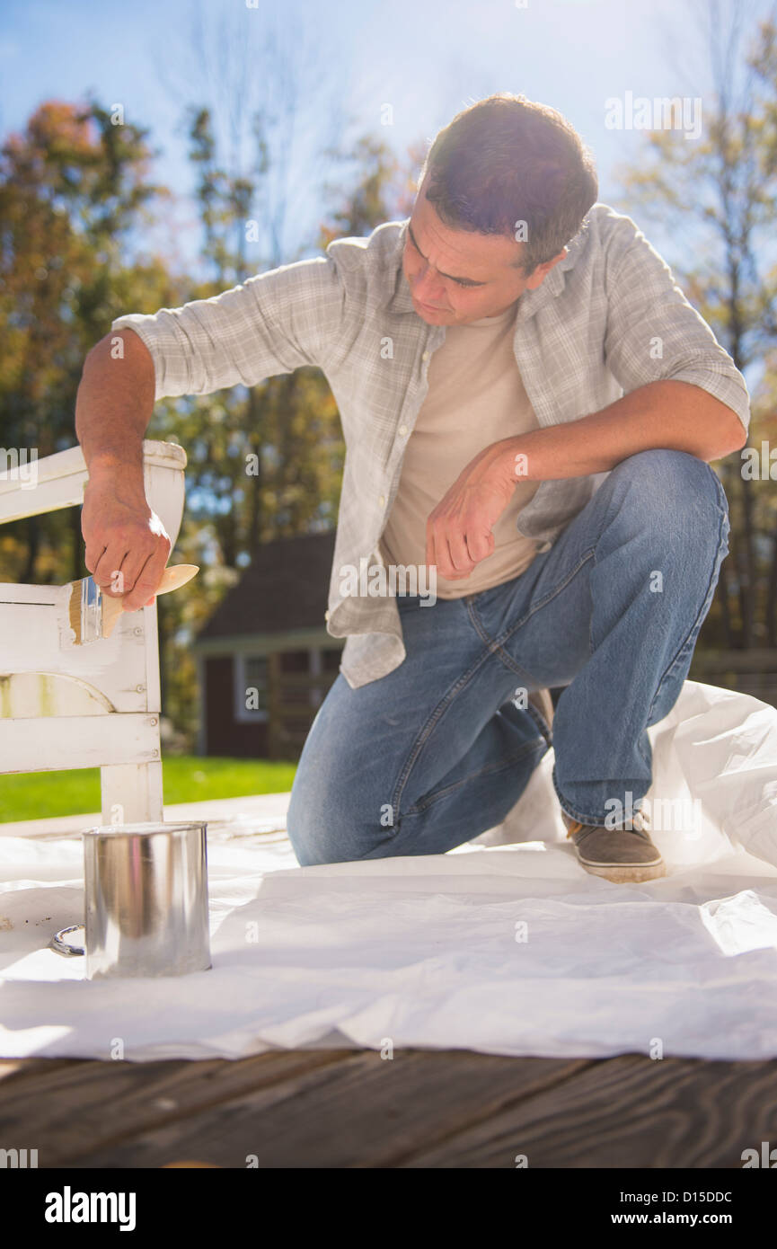 USA, New Jersey, Mendham, Portrait of man painting deck chair Stock Photo
