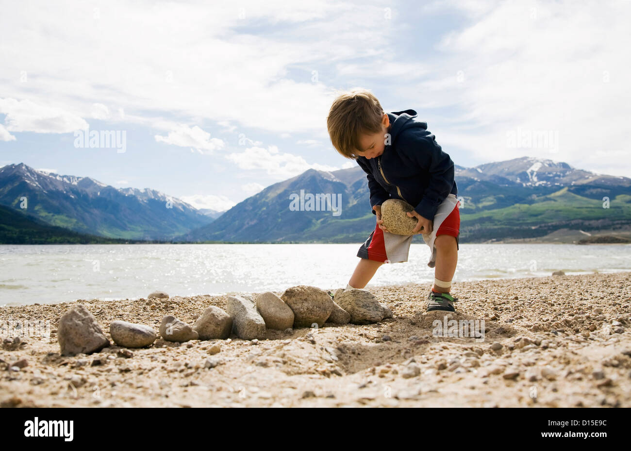 USA, Colorado, Boy (2-3) with rocks on beach Stock Photo