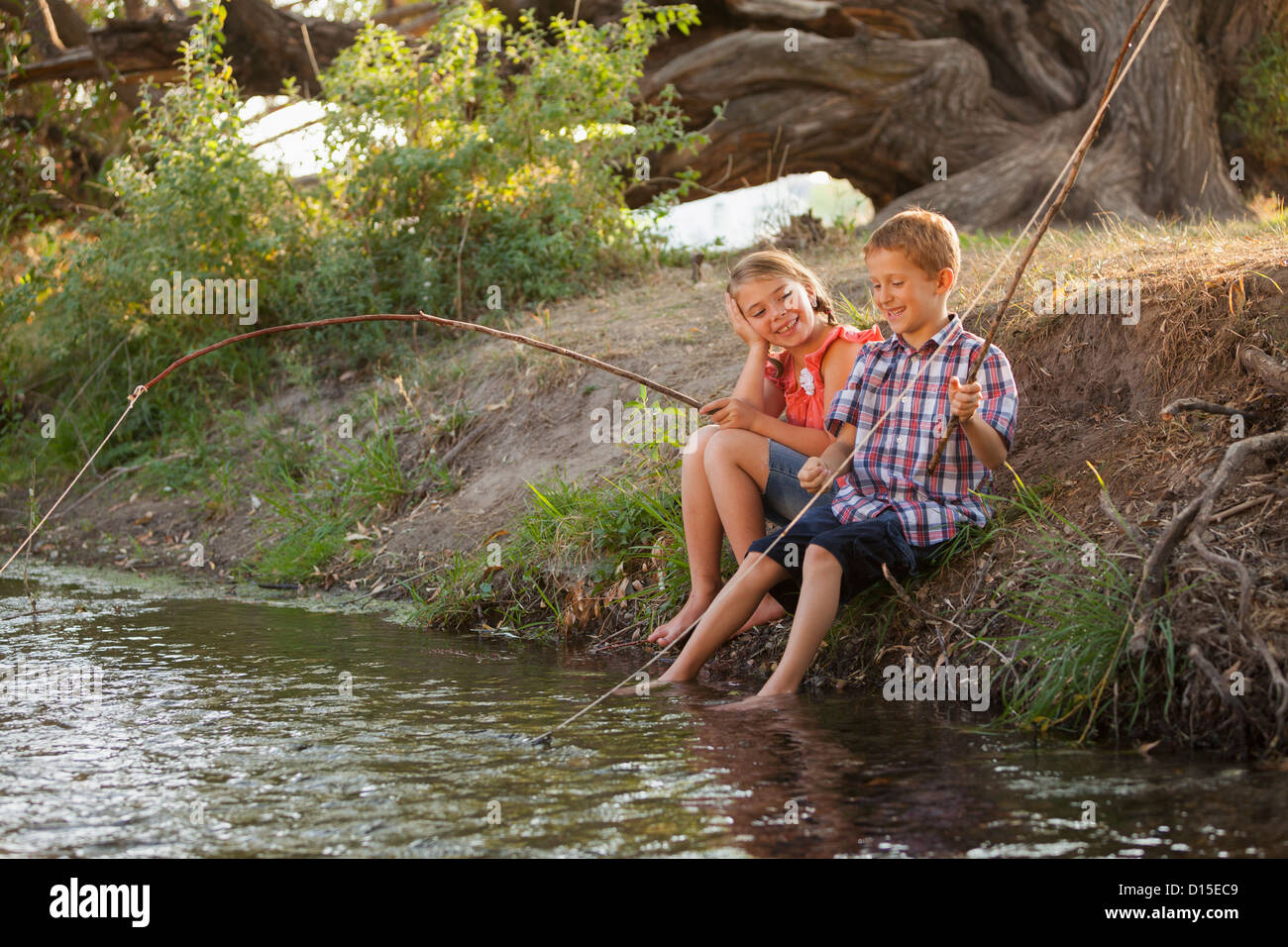 USA, Utah, Lehi, Small boy and girl (6-7) fishing together with makeshift wooden stick in fishing poles in small stream Stock Photo