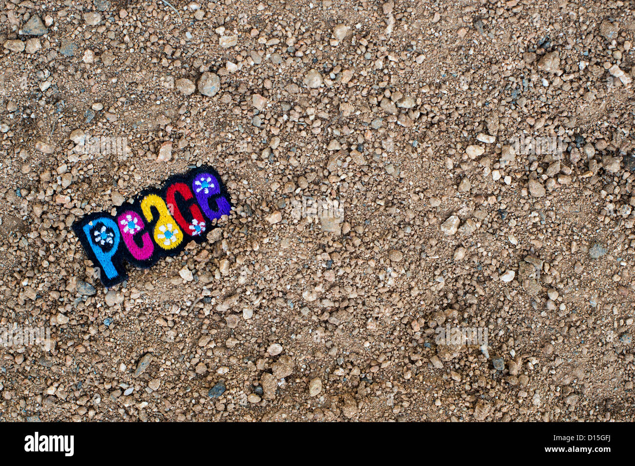 Multicoloured embroidery PEACE patch on a dirt track. India Stock Photo