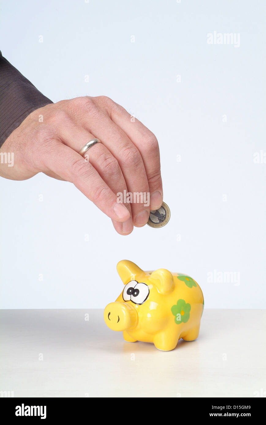 Hamburg, Germany, a Maennerhand put a euro into the piggy bank Stock Photo