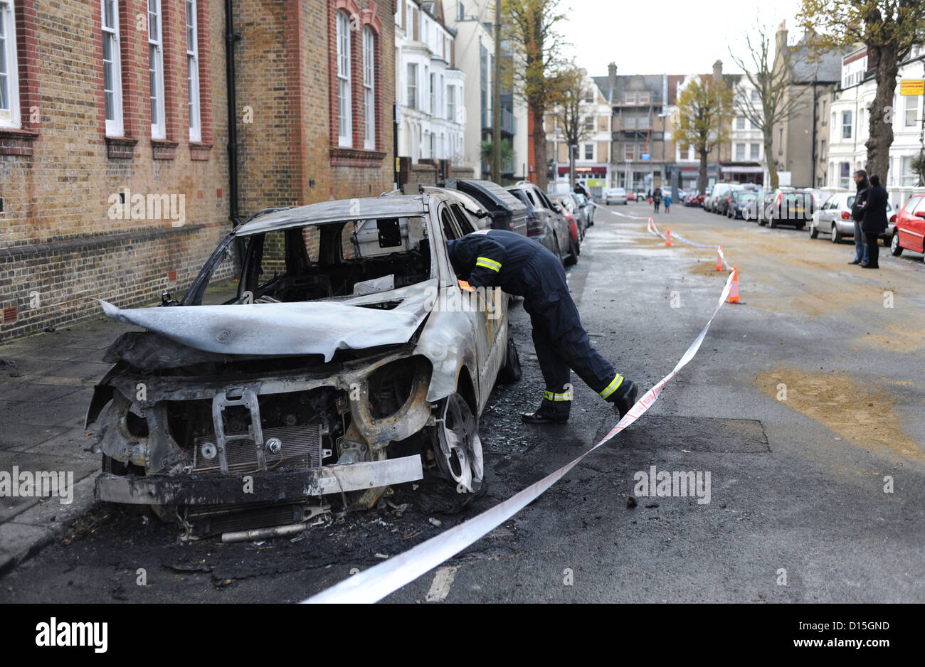 A Fire Investigation Officer checks out the burnt out cars in Connaught Road Hove this morning .  Brighton Sussex UK 2012 Stock Photo