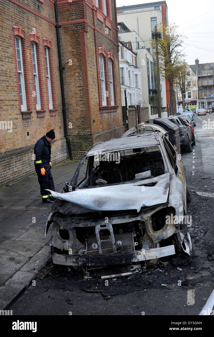 A Fire Investigation Officer checks out the burnt out cars in Connaught Road Hove this morning .  Brighton Sussex UK 2012 Stock Photo