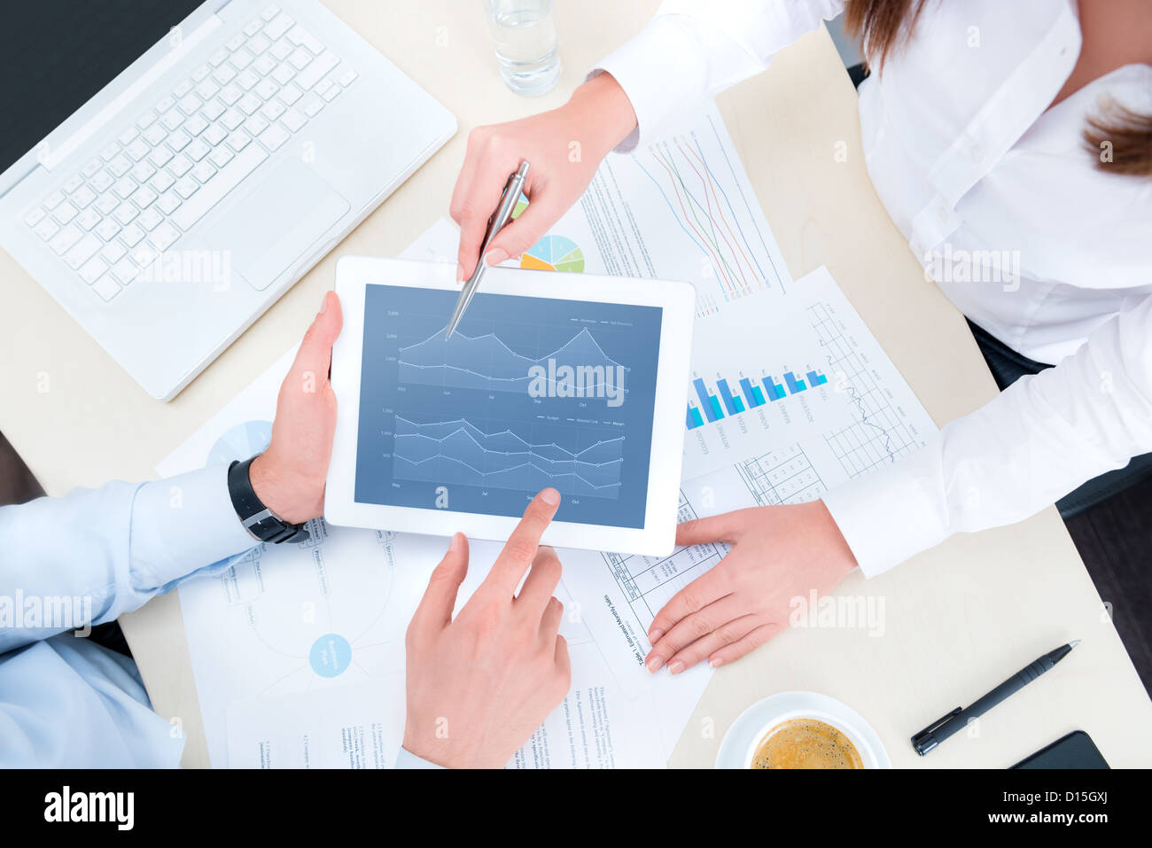 Businessman and businesswoman analyzing financial report on a modern digital tablet. Top view shot. Stock Photo