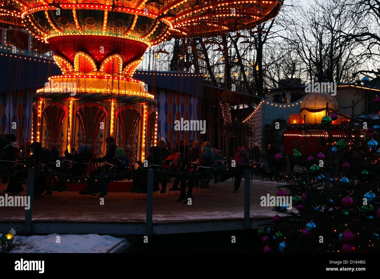 The Swing Carousel, Christmas trees and decorations at dusk at  Christmas market in the snow covered Tivoli Gardens, Copenhagen, Denmark Stock Photo
