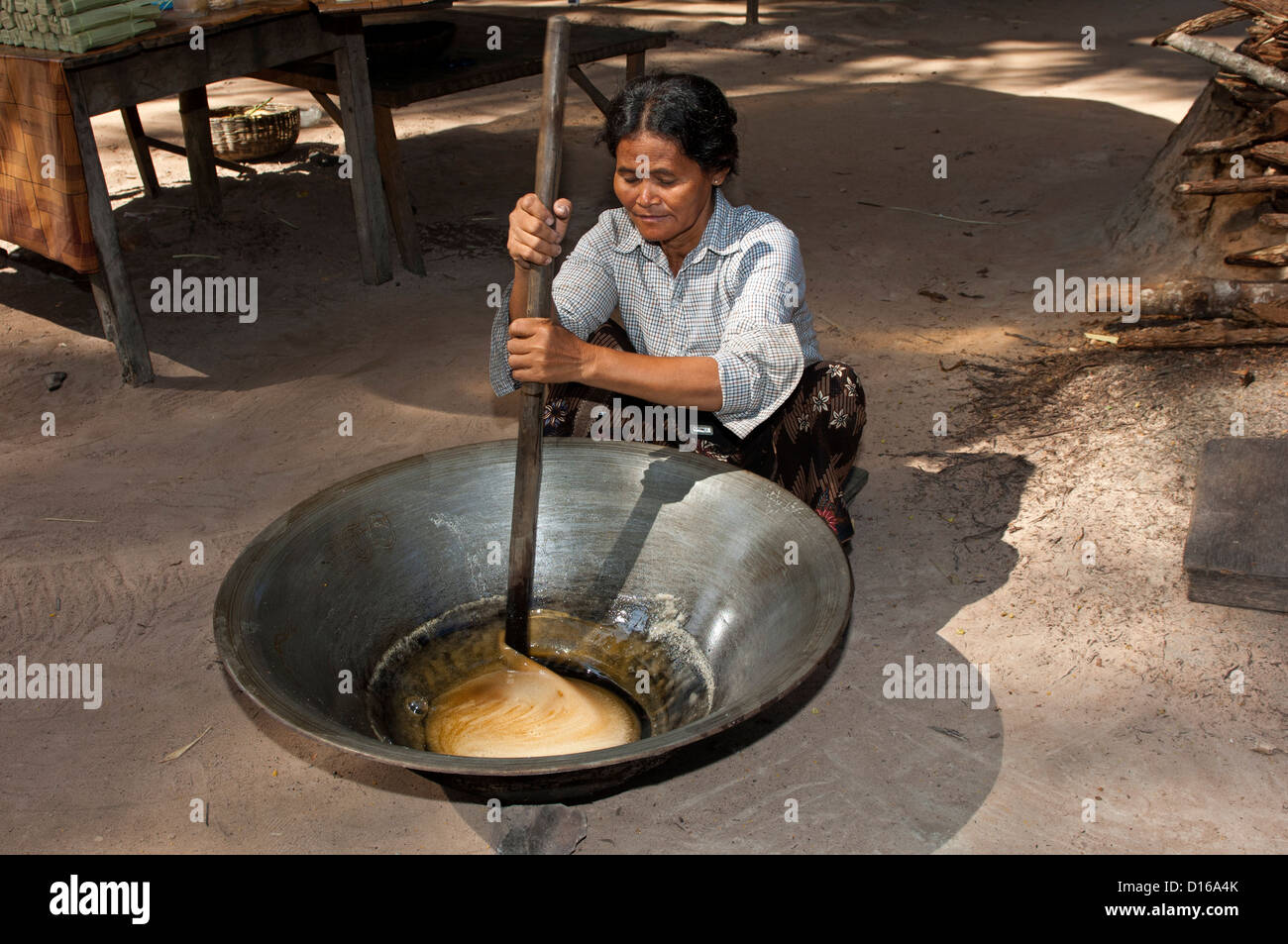 Khmer woman stirring palm sap in a heated traditional metal pan to palm sugar, called Skor Tnout, Siem Reap, Cambodia Stock Photo