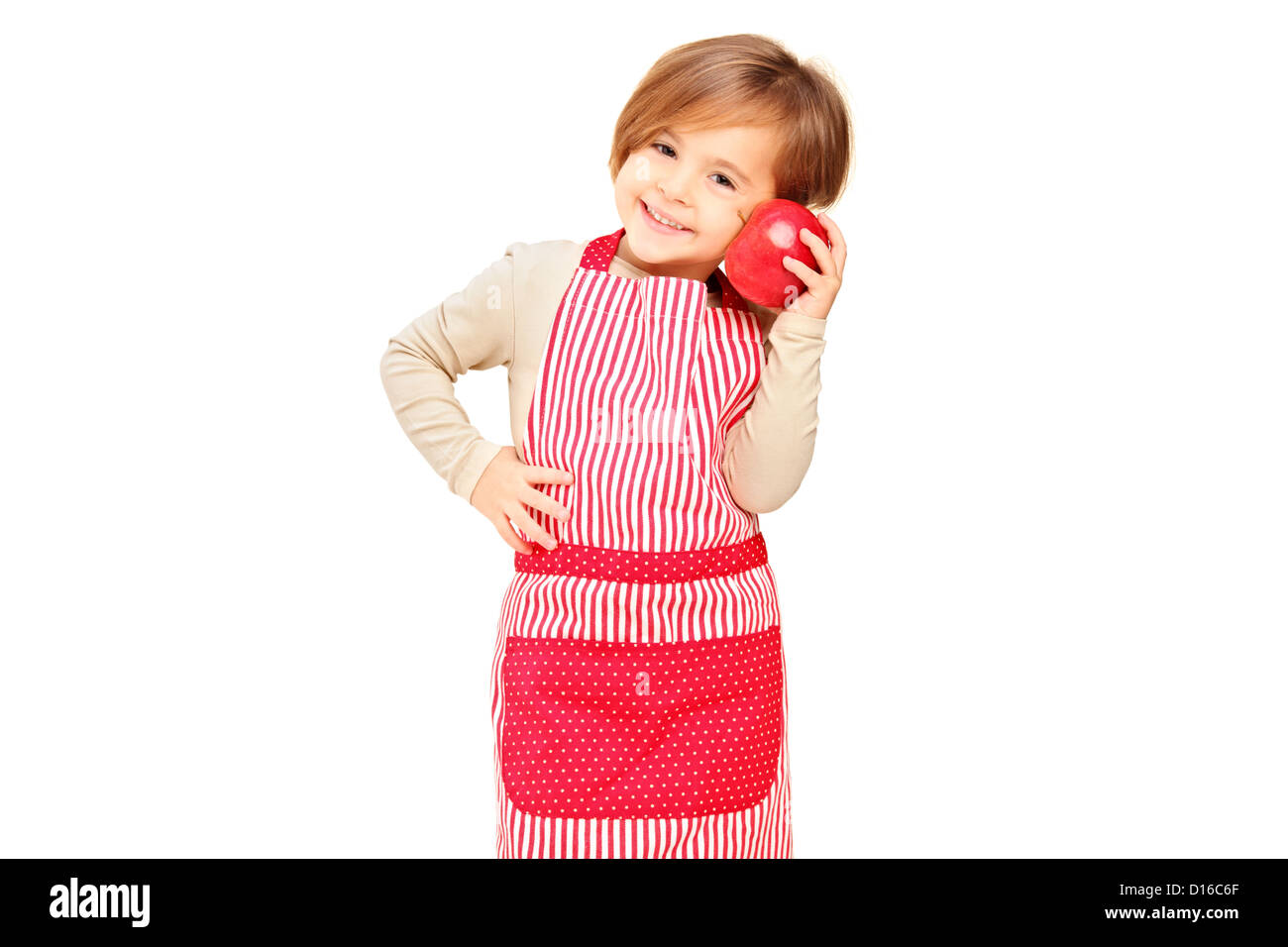 A smiling girl with apron holding a red apple isolated against white background Stock Photo