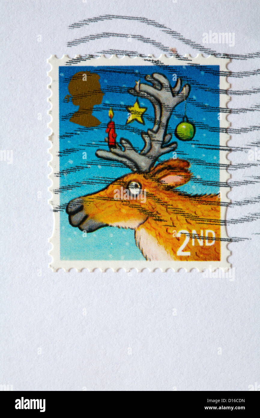 2nd class stamp with reindeer with bauble star and candle hanging from antlers stuck on white envelope and franked Stock Photo