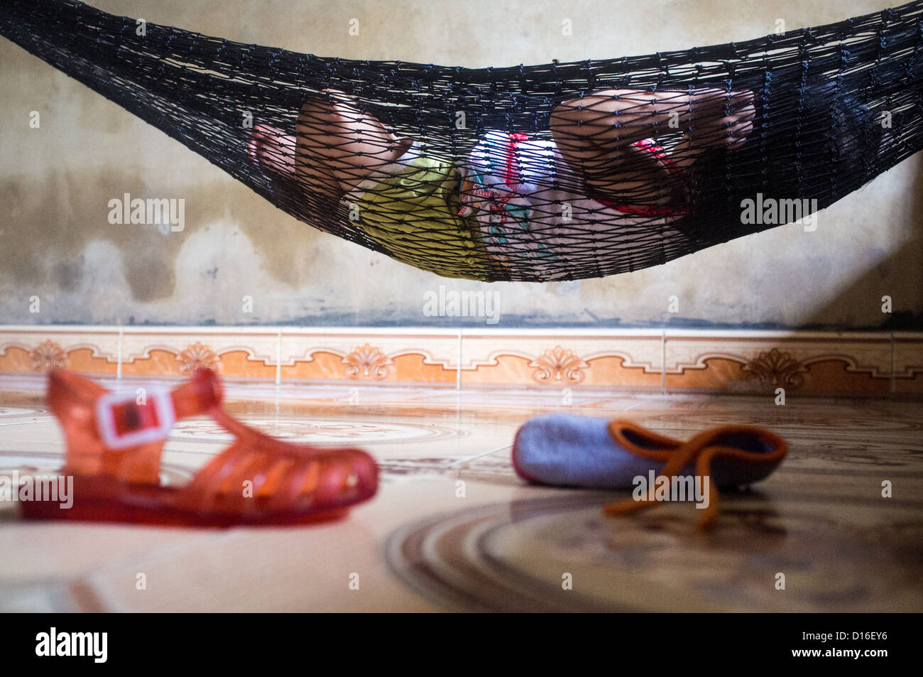 Baby sleeping in an hammock with various footwear in the foreground