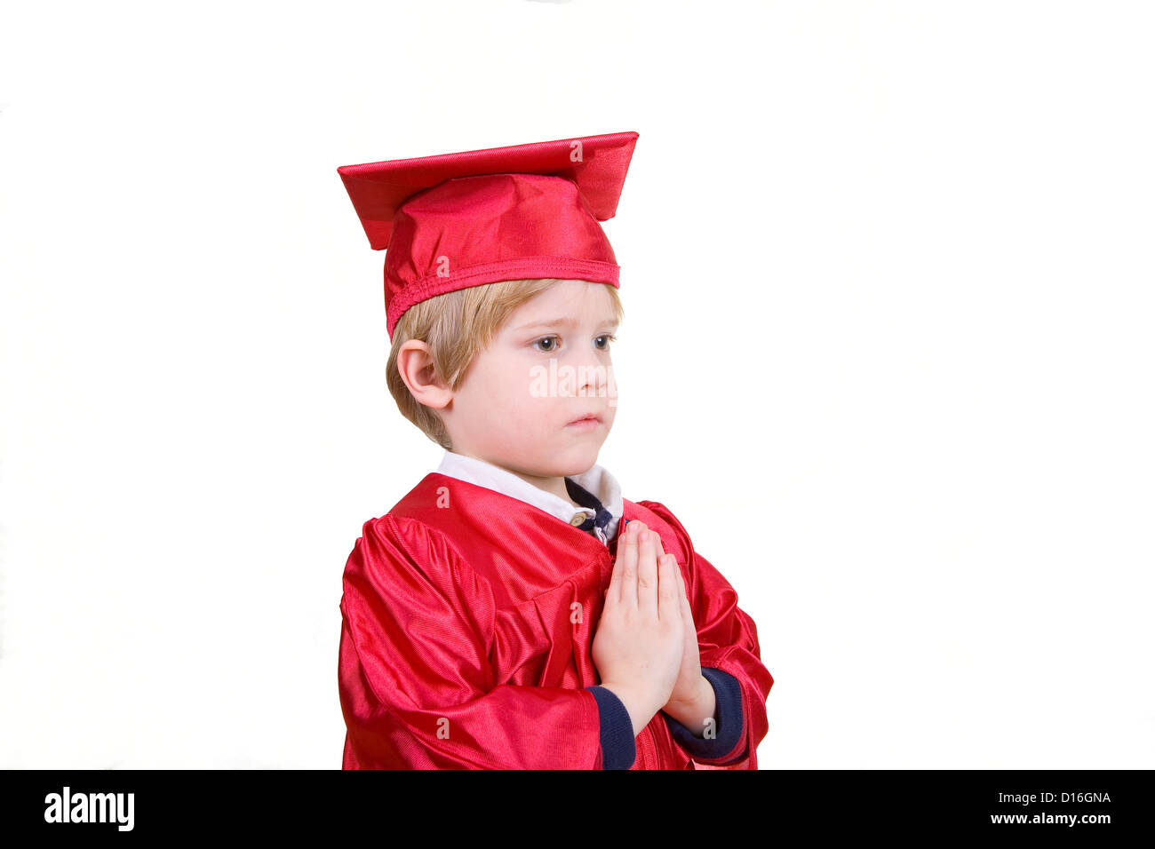 A boy in a red graduation gown with his hands in a prayer pose Stock Photo
