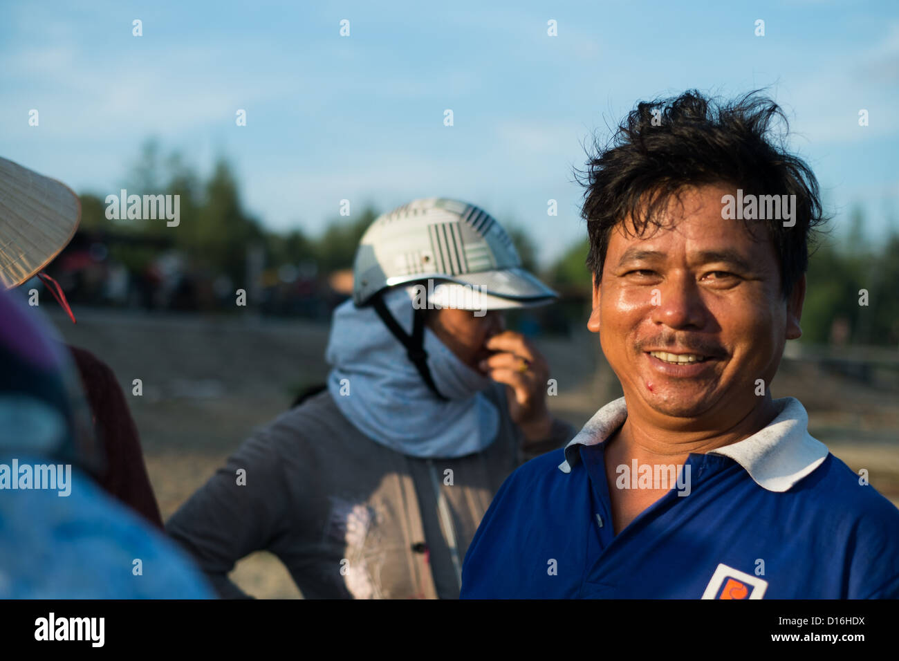 Smiling Vietnamese male in warm sunlight wearing a blue polo short with white collar Stock Photo