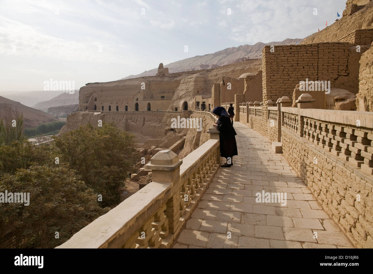 A muslim woman stands at the Bezaklik Thousand Buddha Caves in Turfan, Xinjiang Province, China Stock Photo