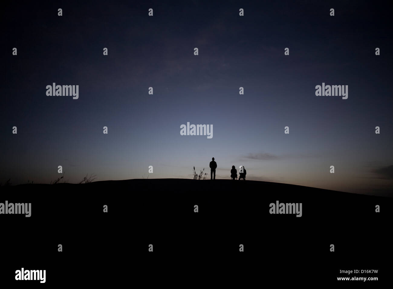Three people are waiting for the sunrise in the Taklamakan Desert, Xinjiang Province, China Stock Photo