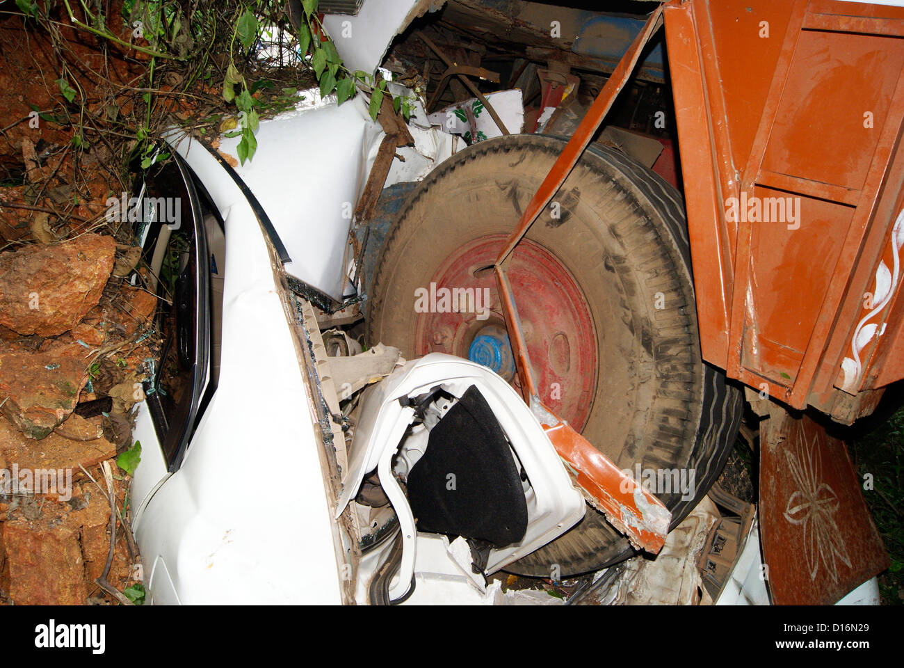 car and Lorry Accident in India.Fully crashed down car and Huge Truck tyres above the top of car Stock Photo