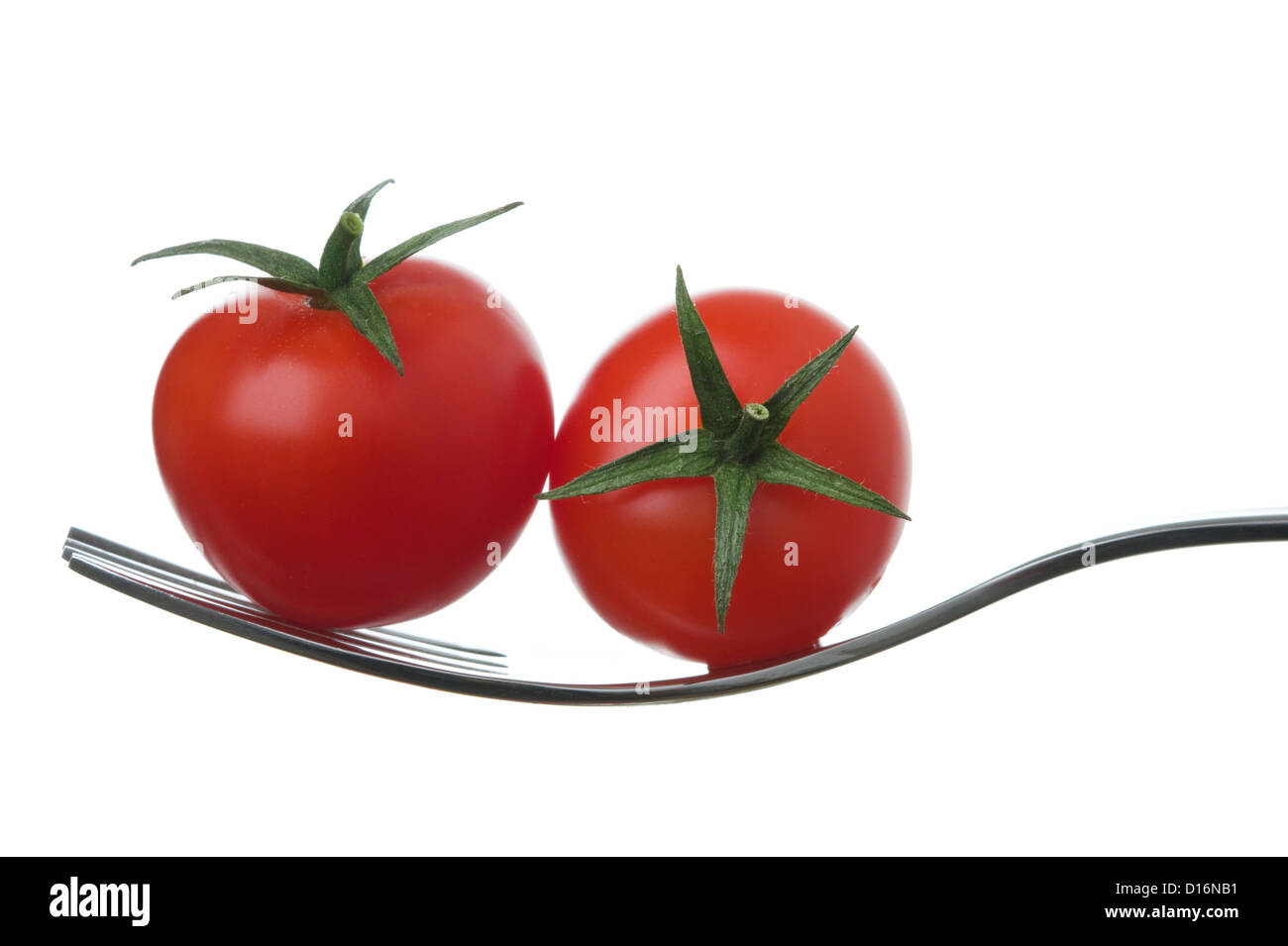 two ripe cherry tomatoes on a fork against white Stock Photo